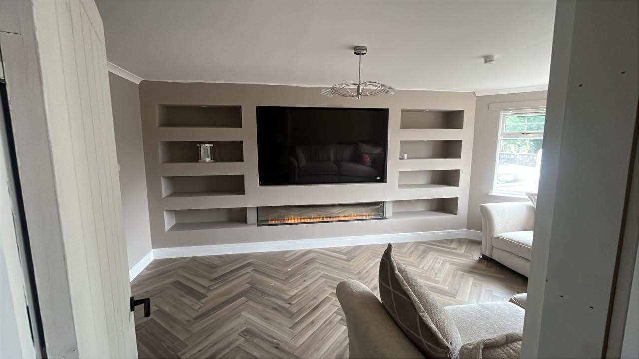 Taupe media wall with fireplace and herringbone floor